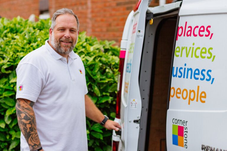 A Cornerstone repairs operative standing beside the open doors of a branded van