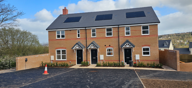 A newly built terrace of three brick homes with solar panels on the roof