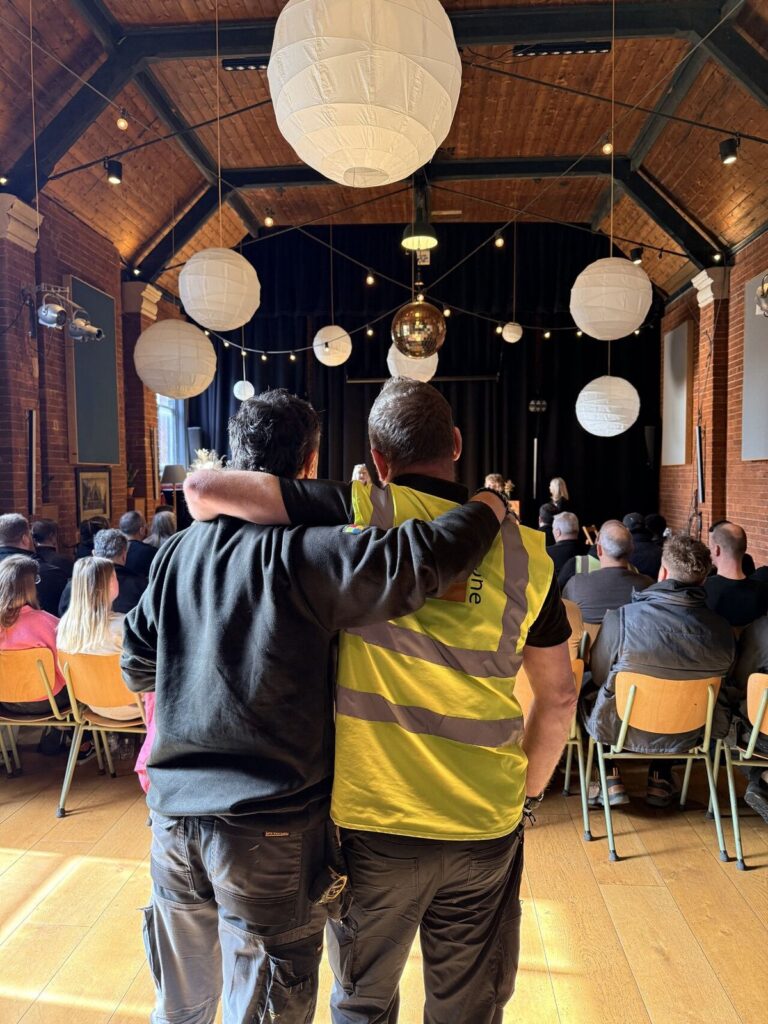 A colleague addressing a seated audience of residents in a hall