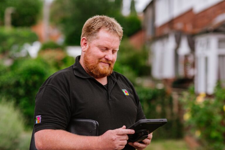 A Cornerstone operative using a tablet outside a row of homes