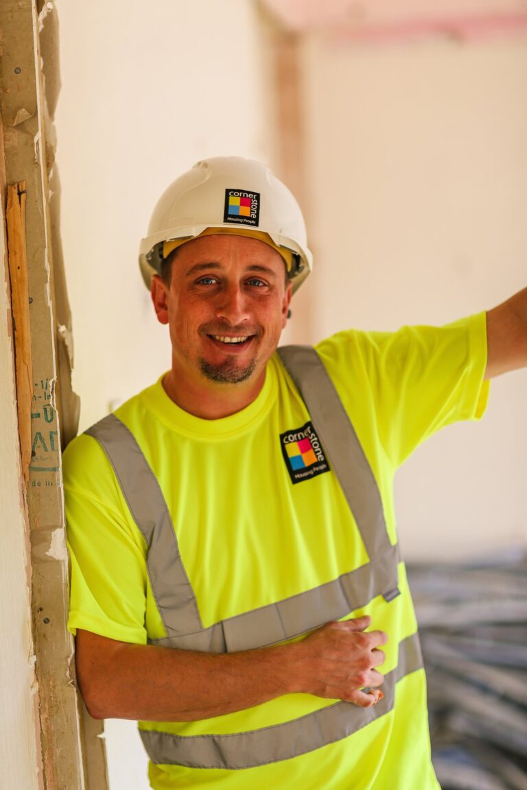 An operative in a hard hat and hi-vis top in a room being refurbished