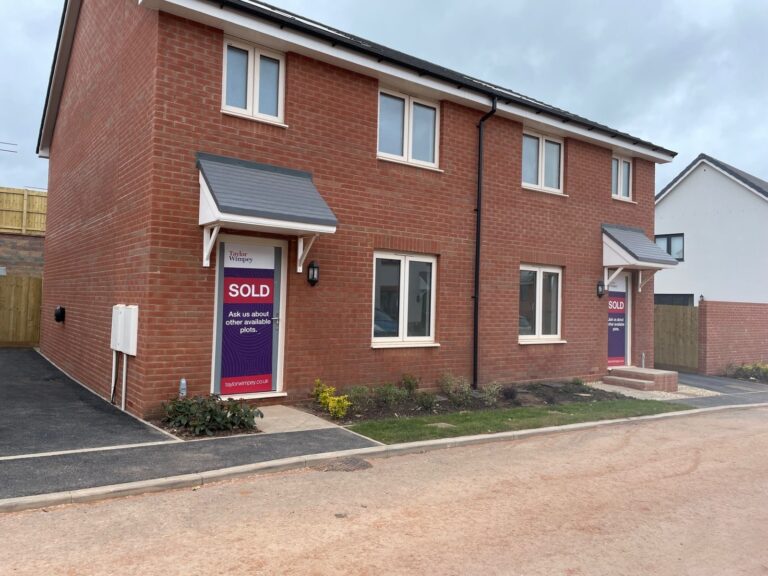 A pair of newly built brick homes with a sold sign outside