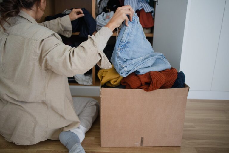 A person packing clothes into a cardboard box