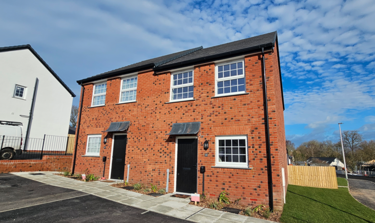 A newly built brick semi-detached home under a blue sky