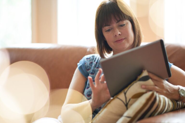 A woman sitting on a sofa using a tablet computer