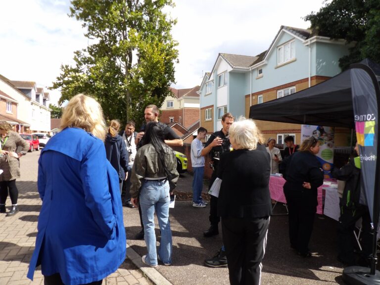 Residents gathered around gazebos at an outdoor community event on a housing estate