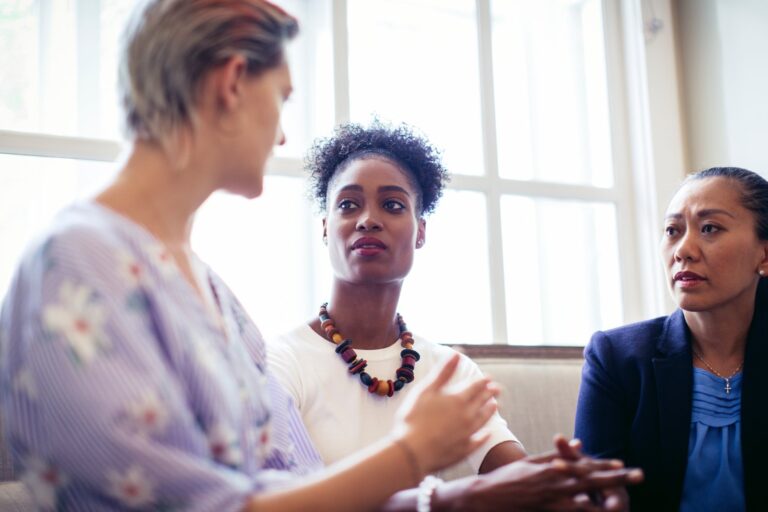 Three women sitting together in conversation during a meeting