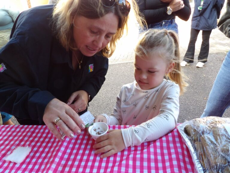 A Cornerstone colleague helping a young girl decorate a cup at a community event