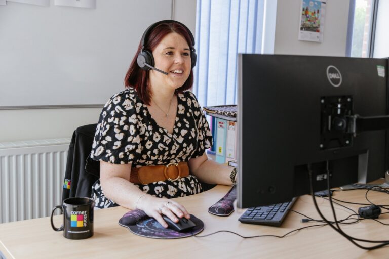 A customer services adviser wearing a headset at her desk
