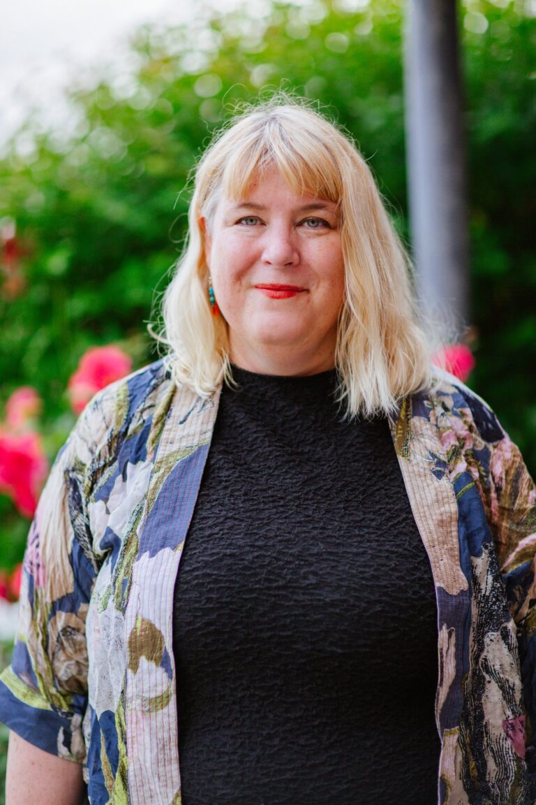 A Cornerstone colleague in a patterned jacket smiling outdoors