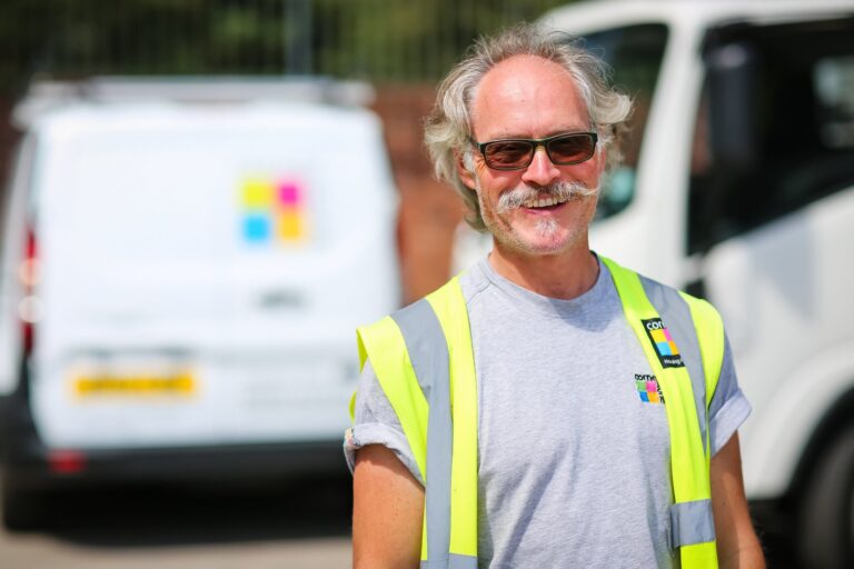 A Cornerstone operative in a hi-vis vest standing beside a works van